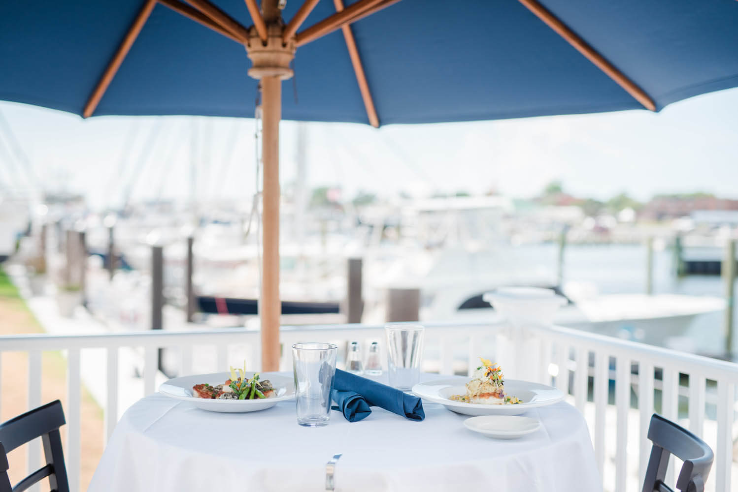 Close up of a restaurant table with two dishes, with harbor in background